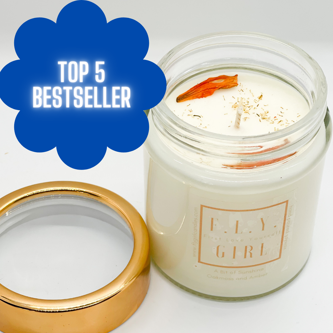 photo of soy candle with gold top and dried lily flower on top on white background product photo